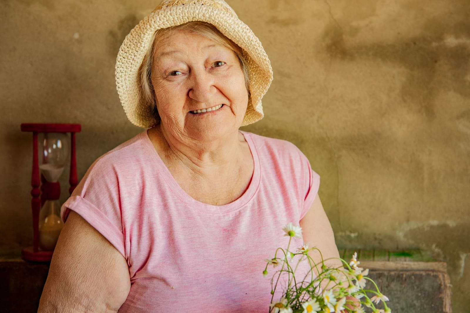 Dona gran amb barret sostenint un ram de margarides